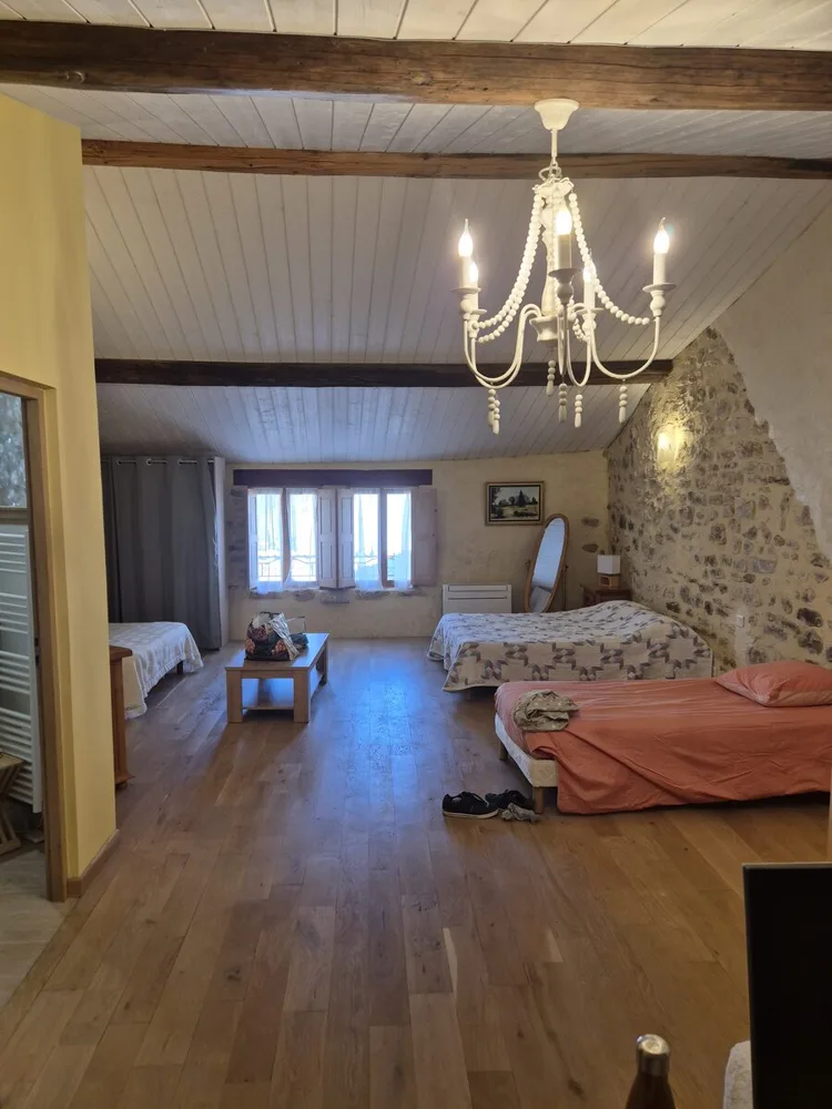 Chambre avec parquet, poutres et mur en pierre apparente