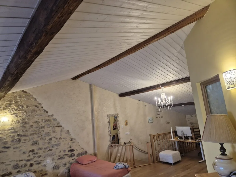 Grande pièce sous combles avec charpente et pignon en pierre