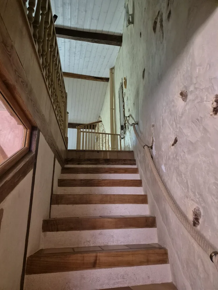 Escalier avec main courante en corde et poutres apparentes