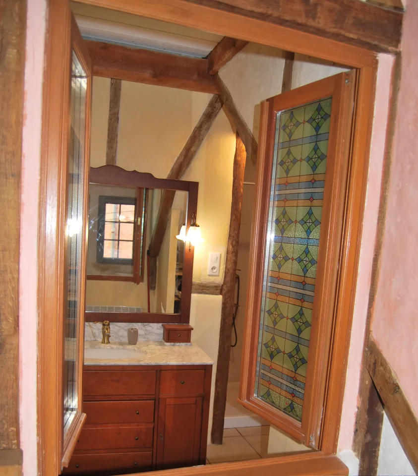 Wooden vanity unit and large mirror, seen from the stained-glass door