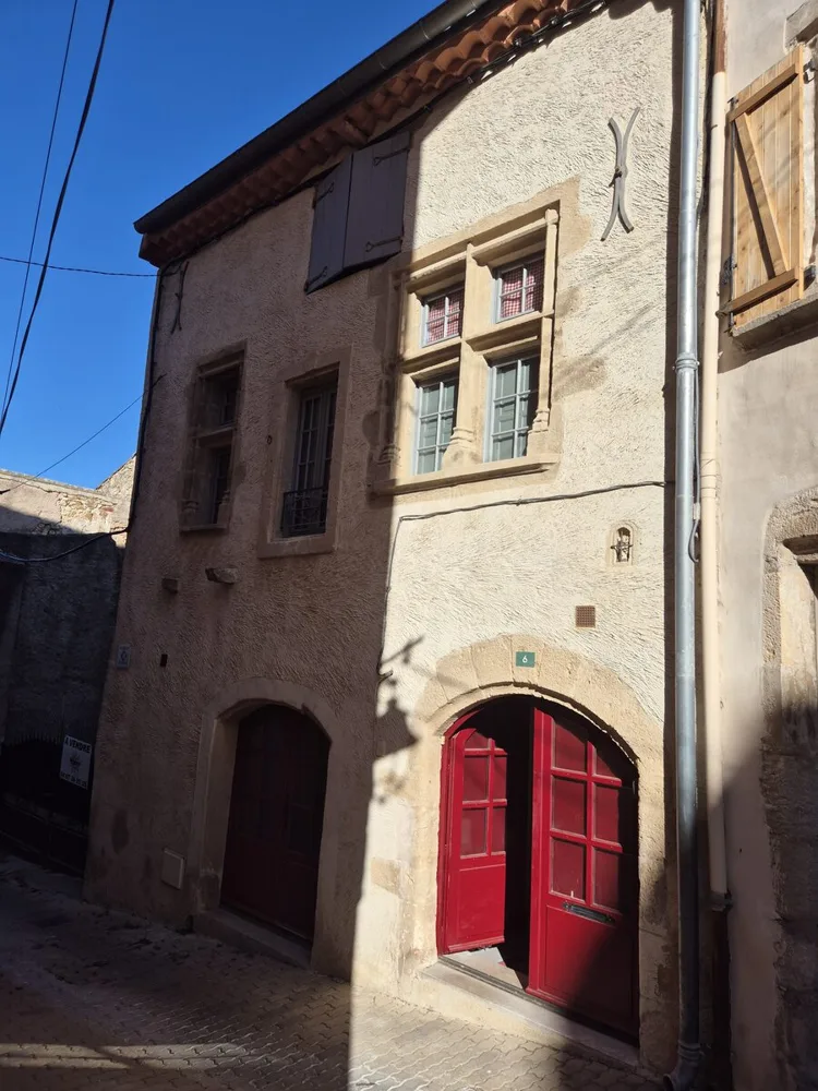 Façade de la maison avec fenêtres à meneaux et porte rouge cintrée