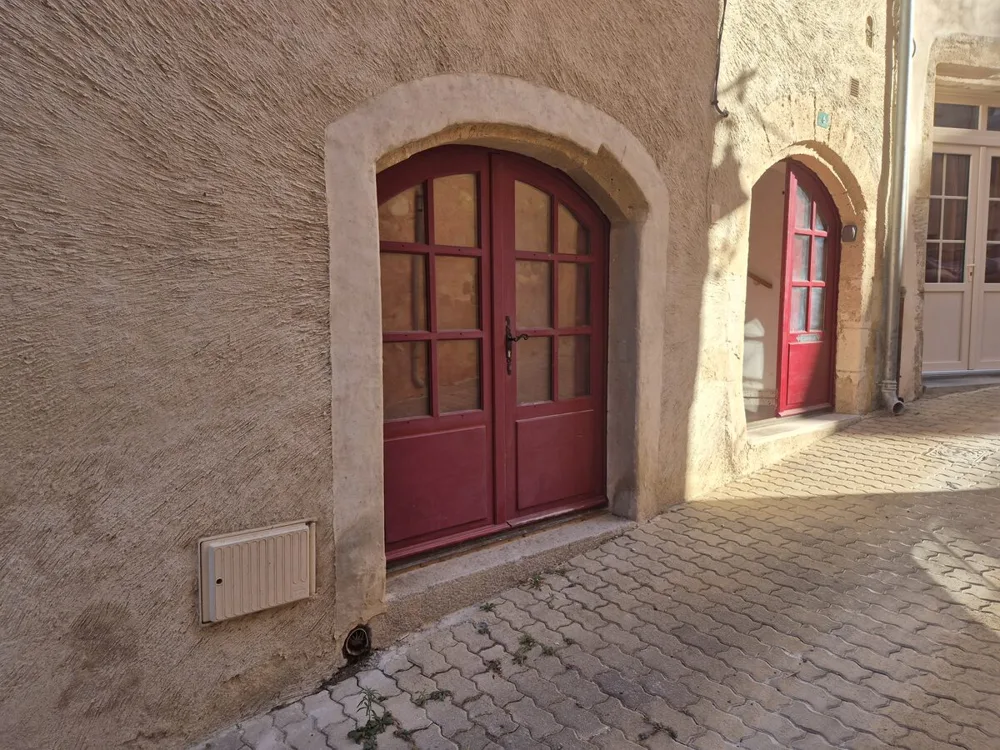 Portes cintrées en bois rouge donnant sur la ruelle pavée