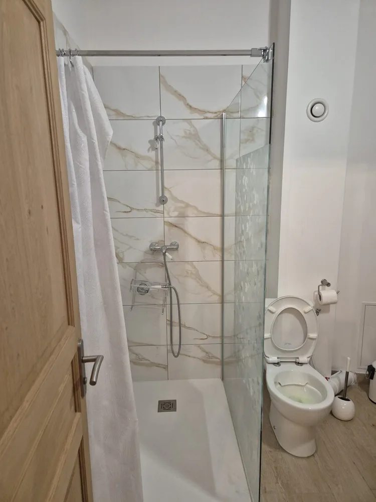 Salle de bains avec baignoire, pare-bain et WC